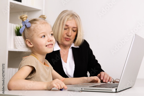 Teacher with little girl typing on the laptop in the classroom