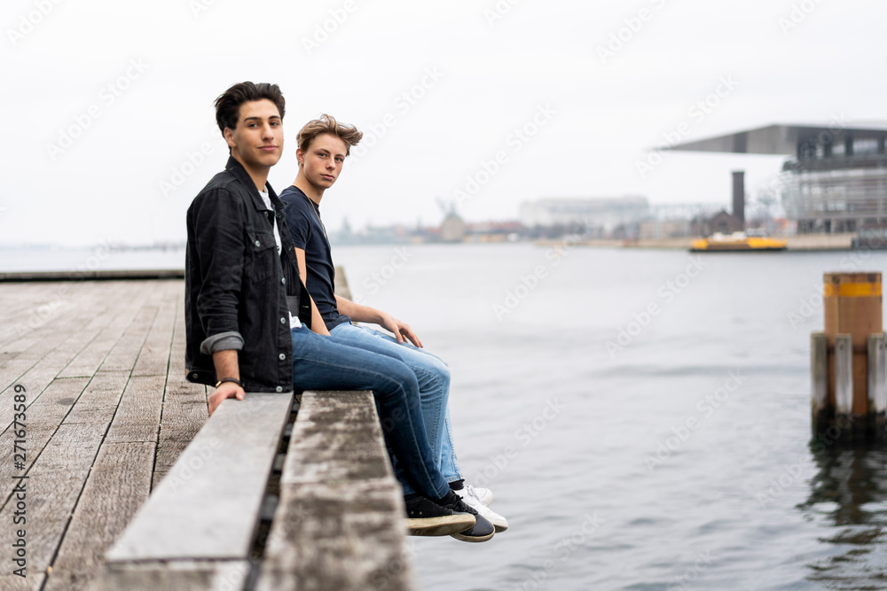 Denmark, Copenhagen, two young men sitting at the waterfront Denmark, Copenhagen, two young men sitting at the waterfront