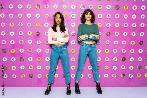 Two young women posing at an indoor theme park with donuts at the wall photo