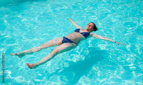 Woman lying on the surface of the water in the pool.