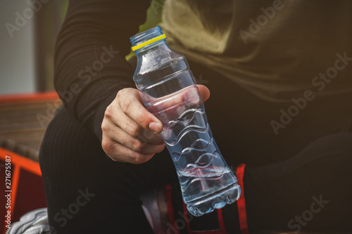 young man in sportsweaat gym holding bottle of water on the sports field