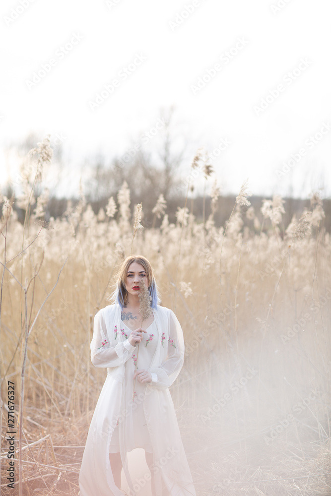 Portrait of young beautiful girl in the white dress in wheat field, walking, carefree. Enjoying the beautiful sunny day