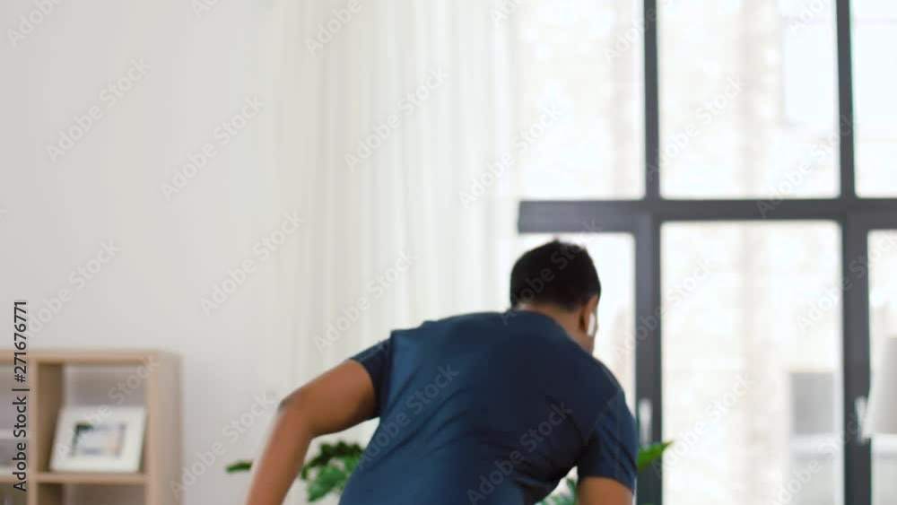 fitness, sport, technology and healthy lifestyle concept - indian man with wireless earphones running on spot at home fitness, sport, technology and healthy lifestyle concept - indian man with wireless earphones running on spot at home