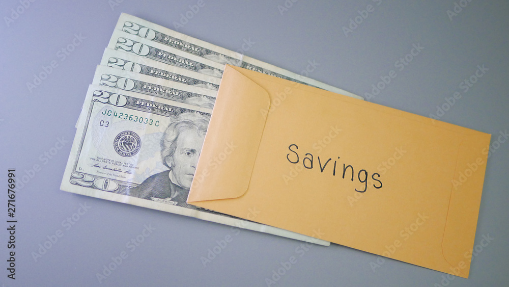 A yellow envelope on a gray table, containing cash for savings. A yellow envelope on a gray table, containing cash for savings.