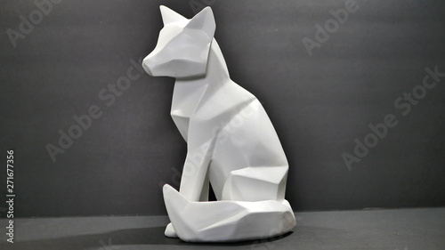 An angle cut polygon wood fox or wolf animal figure statue, painted white on a black background.