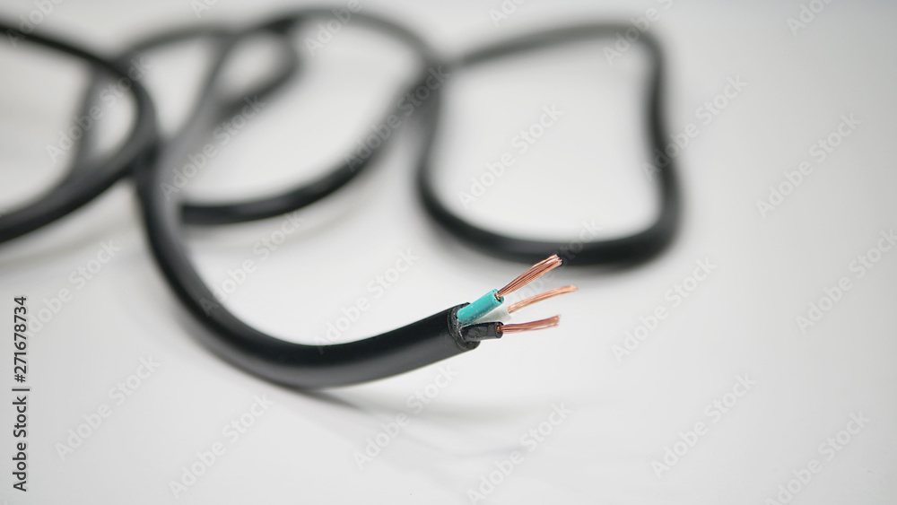 A close-up shot of a black power cord with stripped end showing green, black,  and white wires with copper strands showing. Stock Photo