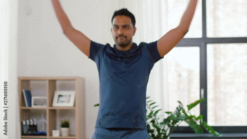 sport, fitness and healthy lifestyle concept - indian man doing jumping jack exercise at home