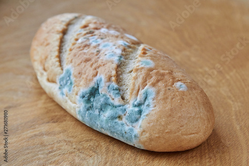 Fotografi Moldy bread on a wooden background. Improper storage of food.