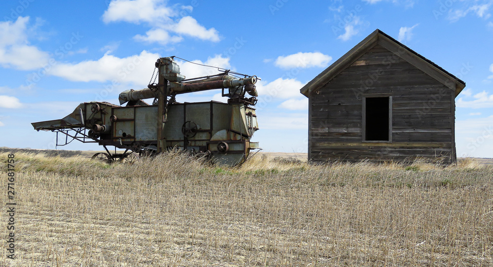 Fototapeta premium A horizontal of abandoned threshing machine and sittind beside is a old grainer.