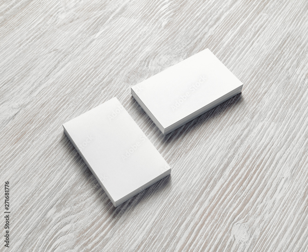 Photo of blank business cards stacks on light wooden background. Template for branding identity.