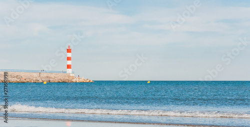 Lighthouse of Port-La-Nouvelle in red and white on cloudy sky © navarro raphael