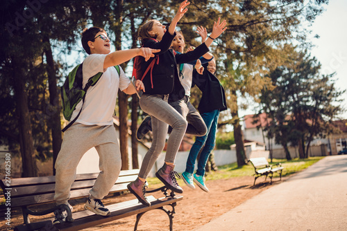 Classmates jumping from bench at schoolyard