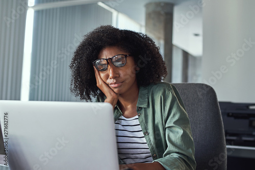 Stressed frustrated young businesswoman looking at laptop photo