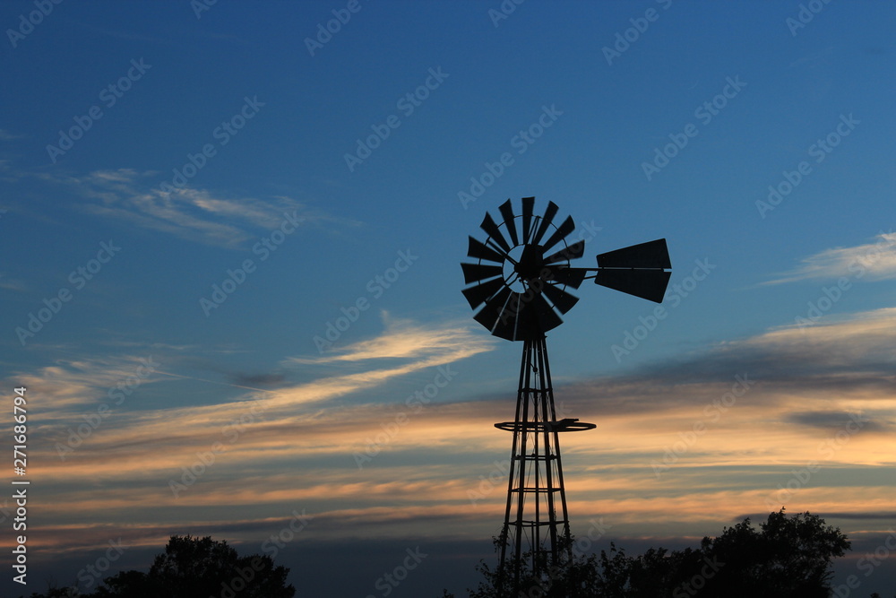 Kansas Windmill silhouette at Sunset with blue sky.