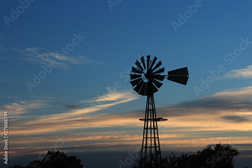 Kansas Windmill silhouette at Sunset with blue sky.