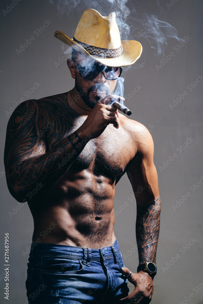 health. smoking cigarette. exhale smoke. bad habit. confidence charisma.  sexy abs of tattoo man. male fashion. muscular macho man with athletic  body. brutal sportsman in cowboy hat. Stock-Foto | Adobe Stock