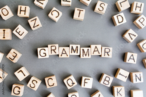 the word grammar wooden cubes with burnt letters, study of grammar of different languages,  gray background top view, scattered cubes around random letters photo