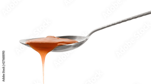 Tasty caramel sauce pouring from spoon isolated on white