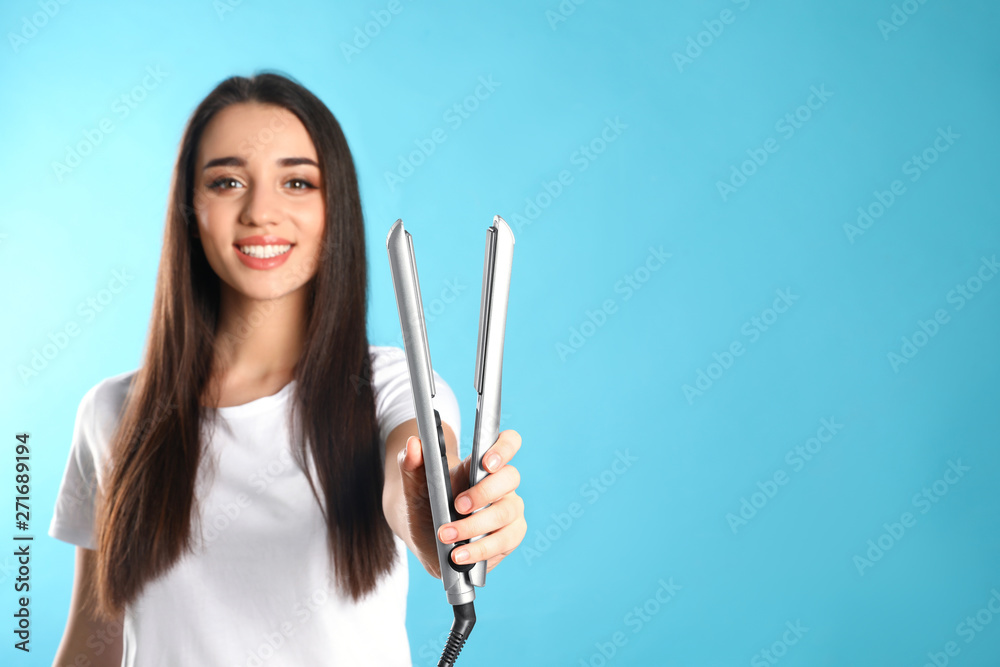 Happy woman with hair iron on color background. Space for text Happy woman with hair iron on color background. Space for text