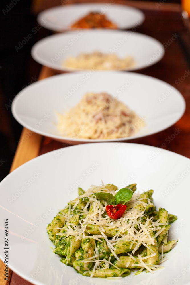 Row of various italian pasta: carbonara, bolognese, pesto penne on a table Row of various italian pasta: carbonara, bolognese, pesto penne on a table