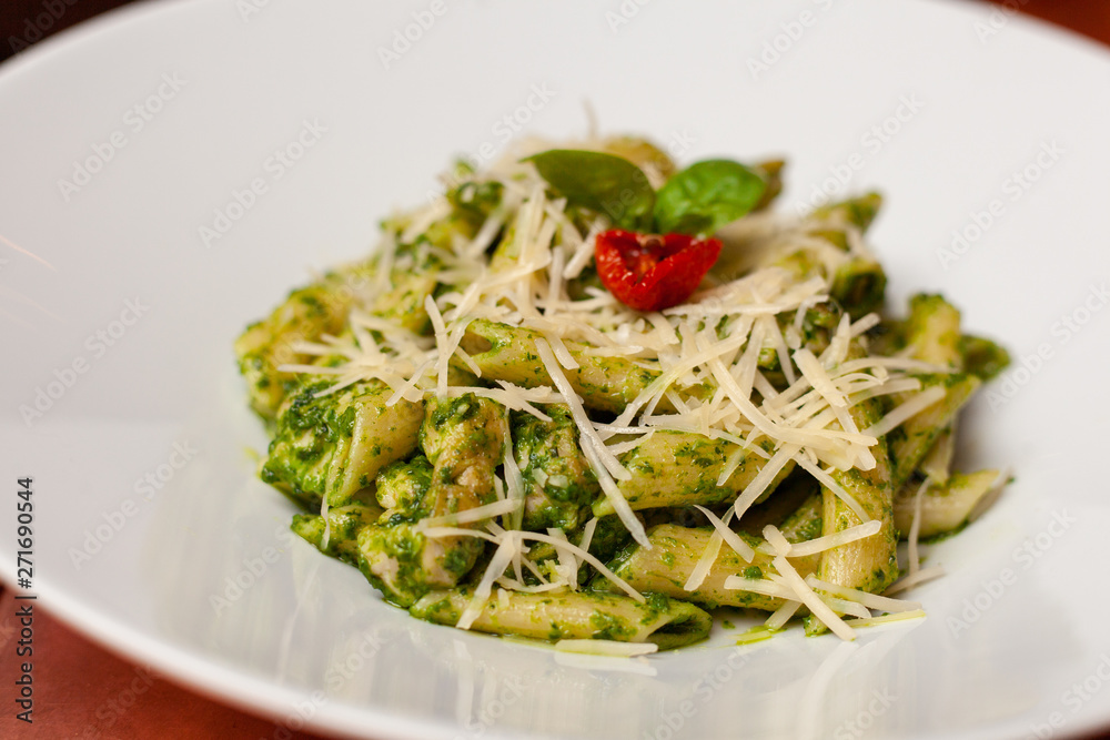 Close-up of classic pesto pasta decorated with basil leaf on white dish