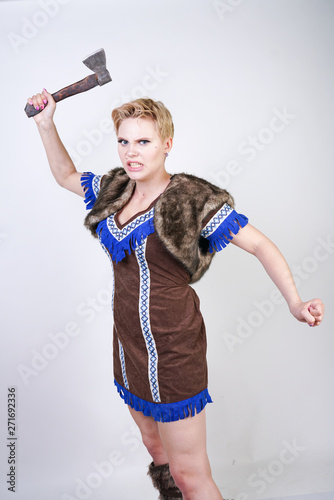 strong woman with short hair and plus size figure in primitive hunter costume with axe aggressively emotionally posing on white background in Studio