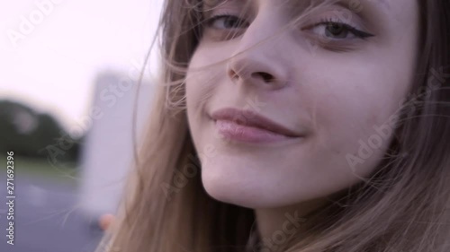 The girl is on the road passing by a car