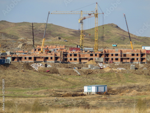 Buildings under construction. Kazakhstan (Ust-Kamenogorsk). Residential buildings. Construction cranes. Construction cranes. Hills. Steppe