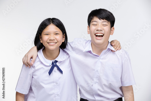 Aasian girl and boy in student's uniform on gray background. photo