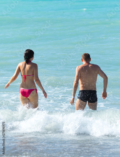 man and woman on the beach in swimsuit, rear view