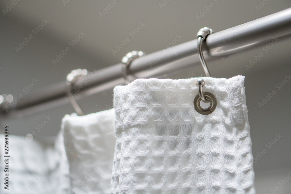 Decorative luxurious shower curtain on hooks.