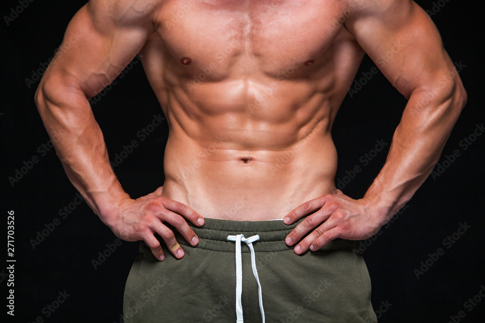 Strong Athletic Man - Fitness Model showing his perfect body isolated on black background with copyspace. Bodybuilder man with perfect abs, shoulders,biceps, triceps and chest. Strong Athletic Man - Fitness Model showing his perfect body isolated on black background with copyspace. Bodybuilder man with perfect abs, shoulders,biceps, triceps and chest.