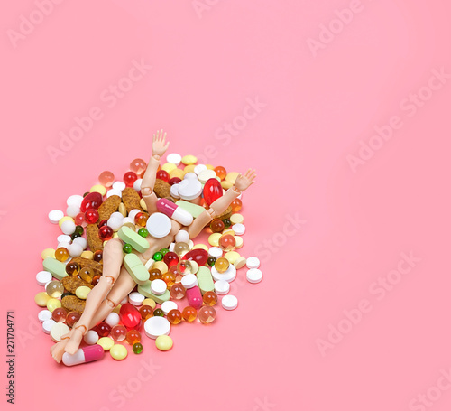 creative concept of dependence on tablets, overdose of medicines. Doll  lies under pile of pills, conceptual image overdose. concept of pharmacological industry. copy space