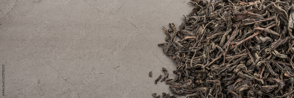 Dried tea is poured scattered on a grey textured background. Dried tea is poured scattered on a grey textured background.
