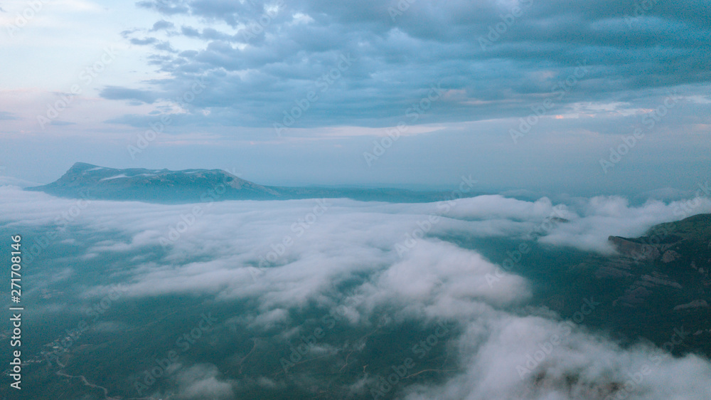 Misty sunrise over the valley and cliffs. Clouds over the mountains.