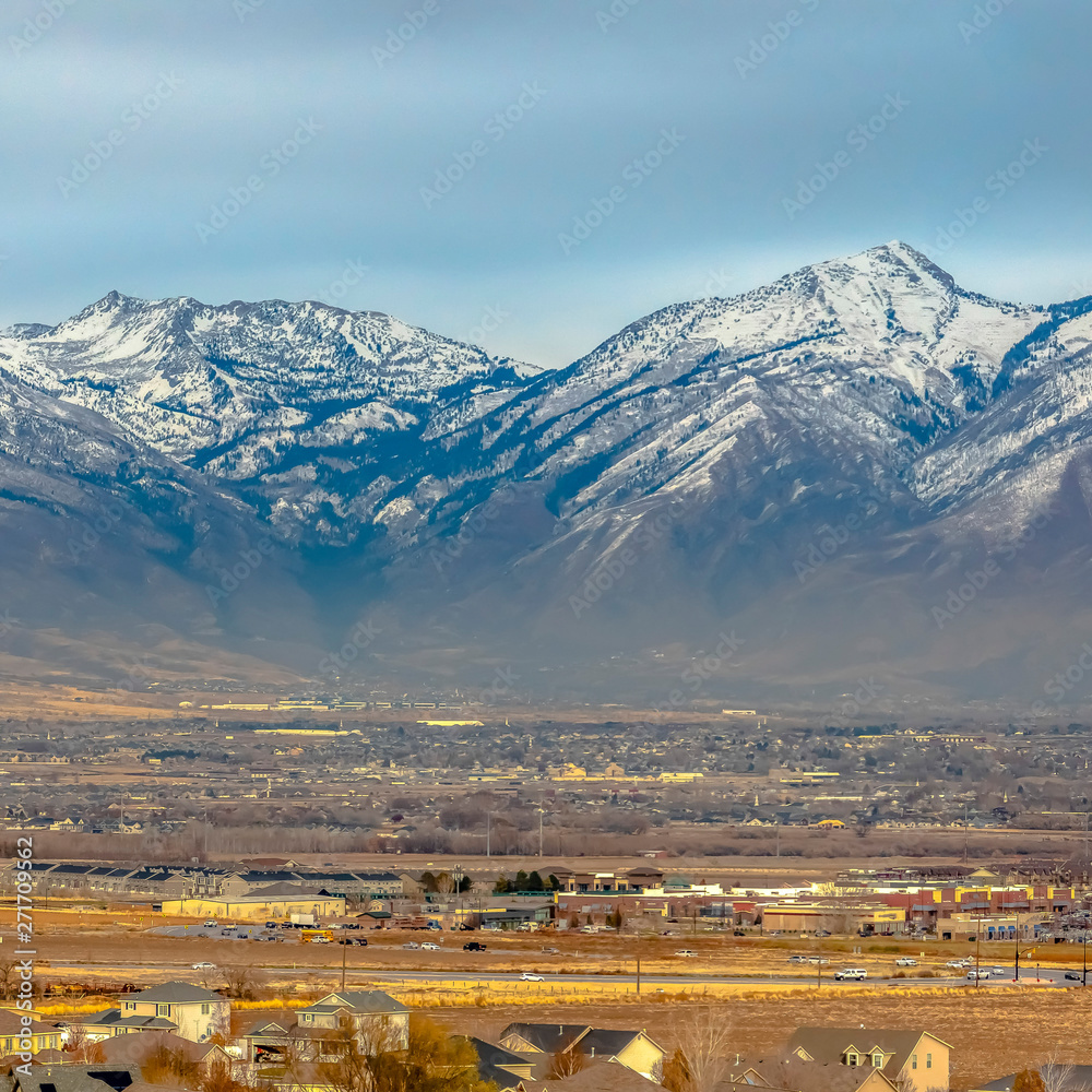 Square Panorama of a snow capped mountain towering over houses in the vast valley Square Panorama of a snow capped mountain towering over houses in the vast valley