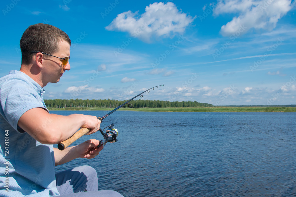 a man in yellow glasses,close-up, against a beautiful landscape, holding a spinning to pull the catch out of the water a man in yellow glasses,close-up, against a beautiful landscape, holding a spinning to pull the catch out of the water