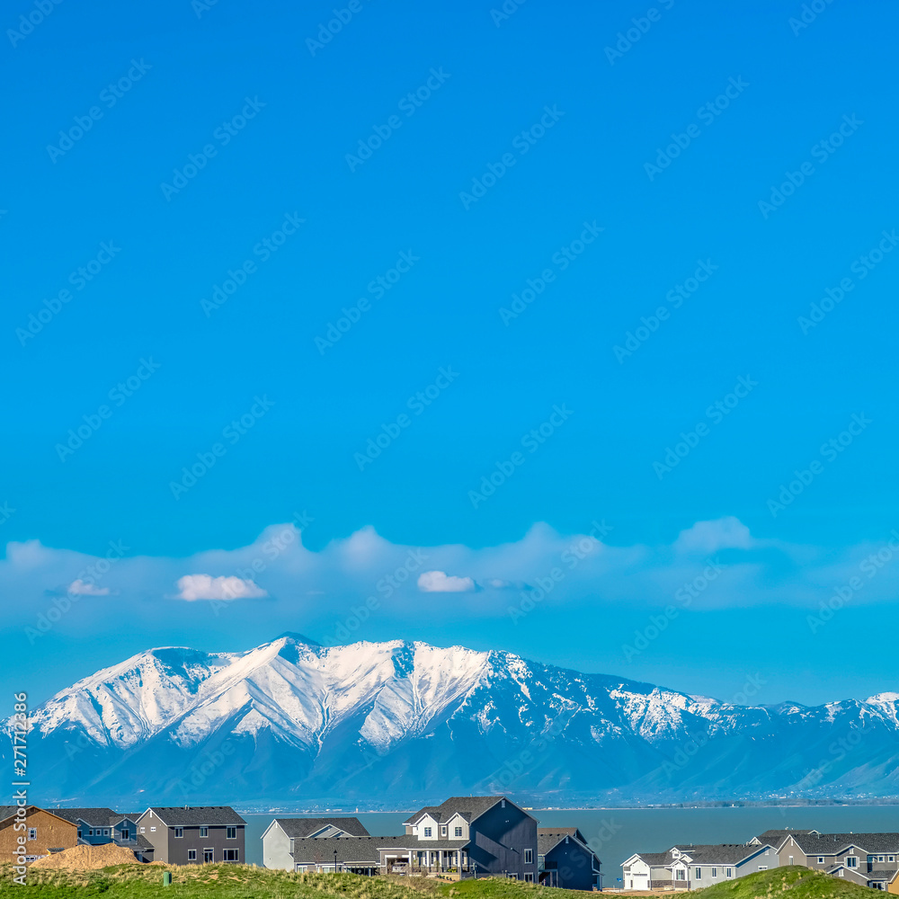 Square Vivid blue sky with clouds over a lake and snow capped mountain on a sunny day