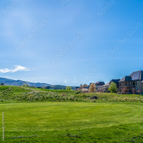 Frame Square Residential houses on a terrain with vivid green grasses viewed on a sunny day