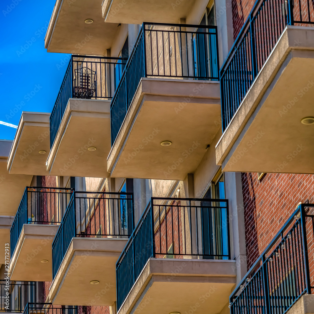 Obraz premium Square Close up of building exterior with brick small balconies and red brick wall