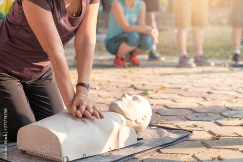 Candid of mature asian female or older runner woman training on CPR demonstrating class in outdoor park and put hands over CPR doll on chest. First aid training for heart attack people or lifesaver. photo