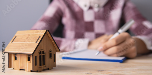 young woman with a dwelling house and documents; real estate agent