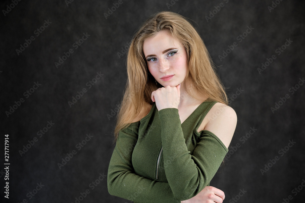Photo portrait of a beautiful girl woman on a dark gray background with long flowing beautiful hair in a green dress standing right in front of the camera and smiling. Photo portrait of a beautiful girl woman on a dark gray background with long flowing beautiful hair in a green dress standing right in front of the camera and smiling.