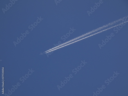 avión surcando el cielo azul y dejando una estela blanca