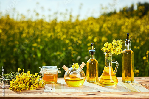 Rapeseed oil bottles (canola) on background rape field photo