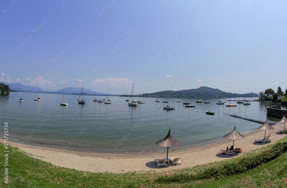 Lake Maggiore beach in a bay with moored sailboats.Italy
