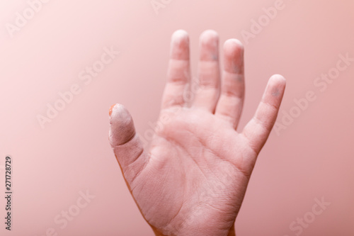 Painted child hand on pink background. Hand in white paint.
