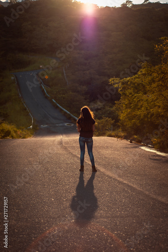 young woman wal on road in sunset