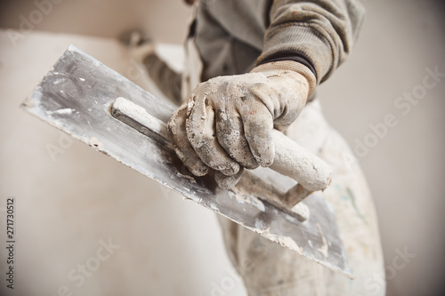 Workman plastering gypsum walls inside the house. photo