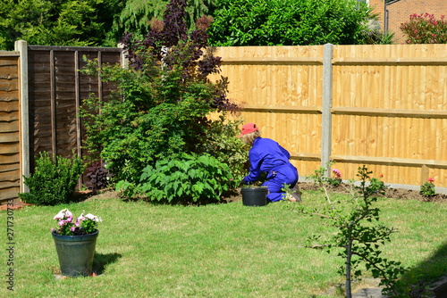 Lady gardening wearing PPE clearing weeds in a garden in the UK